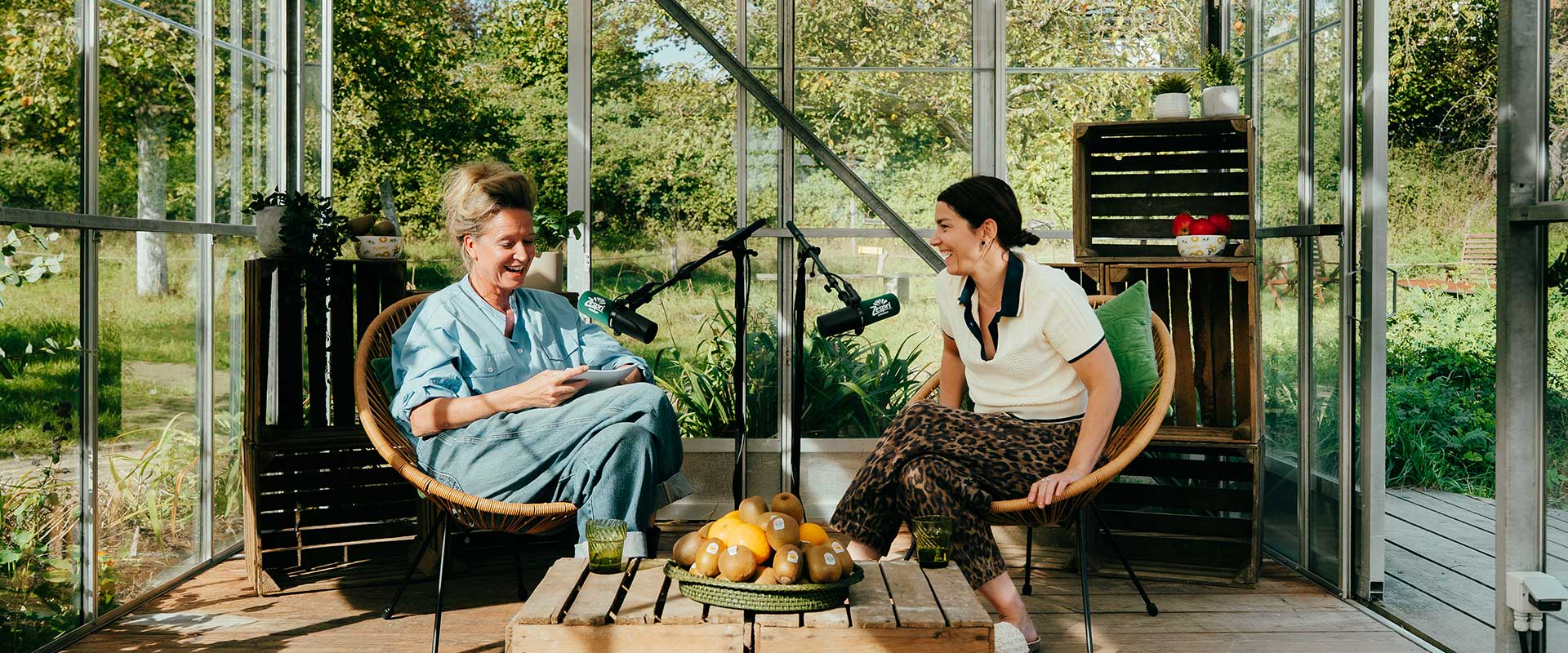Cath Luyten en Magali Surmont zitten in een stoel en praten in een microfoon tegen elkaar - Header 