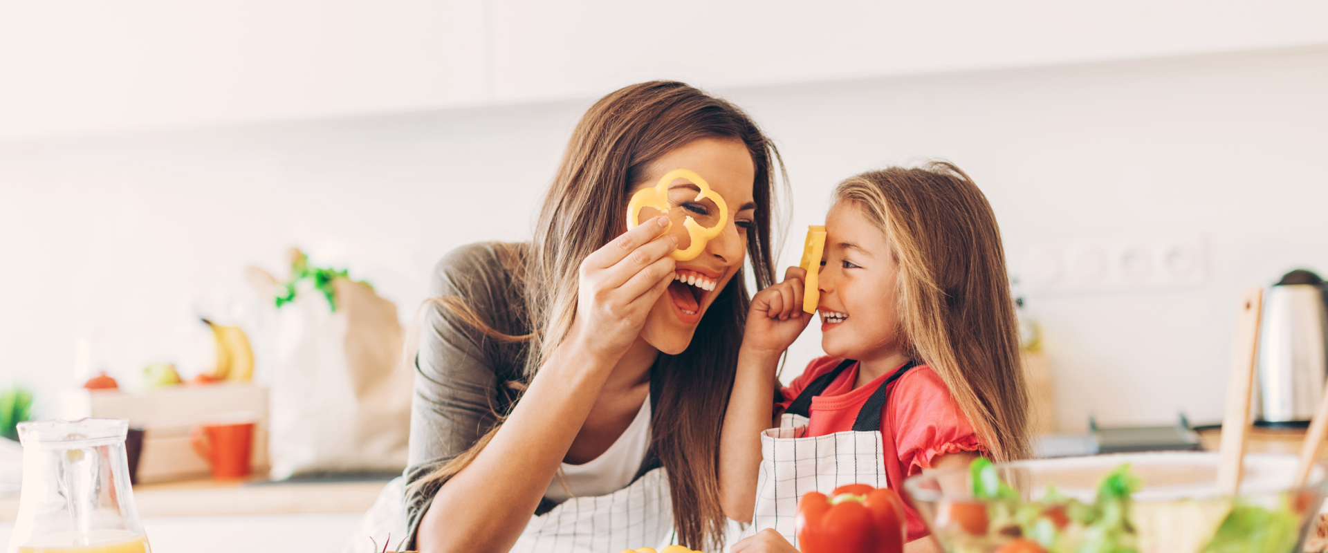 Moeder en dochter koken samen en spelen met groenten in de keuken - Header