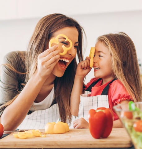 Moeder en dochter koken samen en spelen met groenten in de keuken - Thumbnail