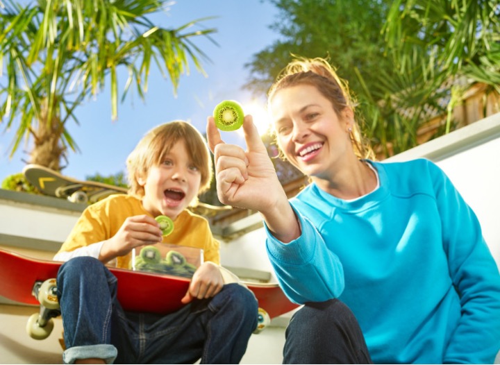 appy and smiling girl eating slices of golden kiwi fruit