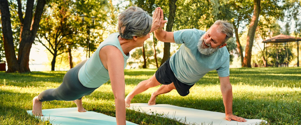 Oudere man en vrouw sporten samen in een park om sterk en fit te blijven