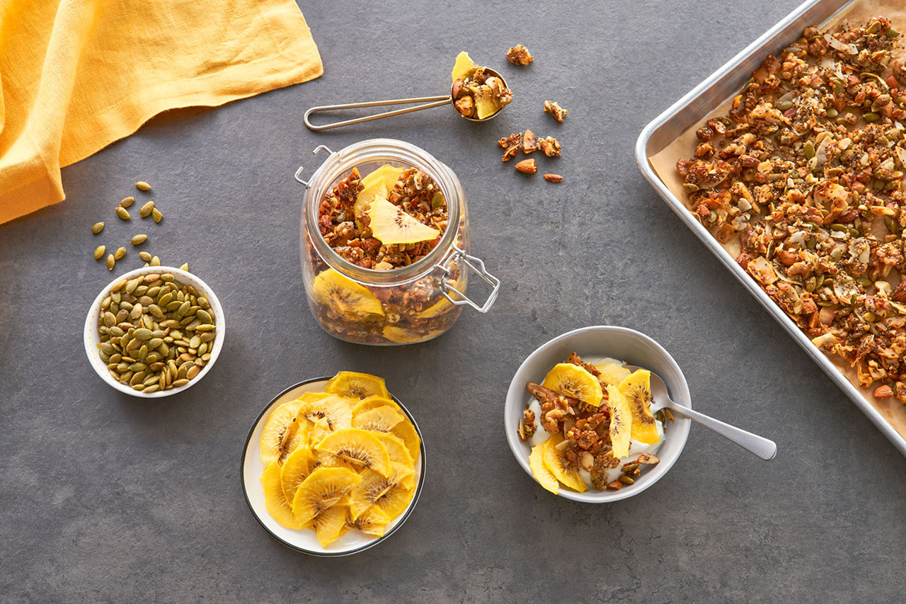 Fresh tray of granola with bowls of Zespri SunGold kiwi fruit and pistachios mixed with vanilla yogurt