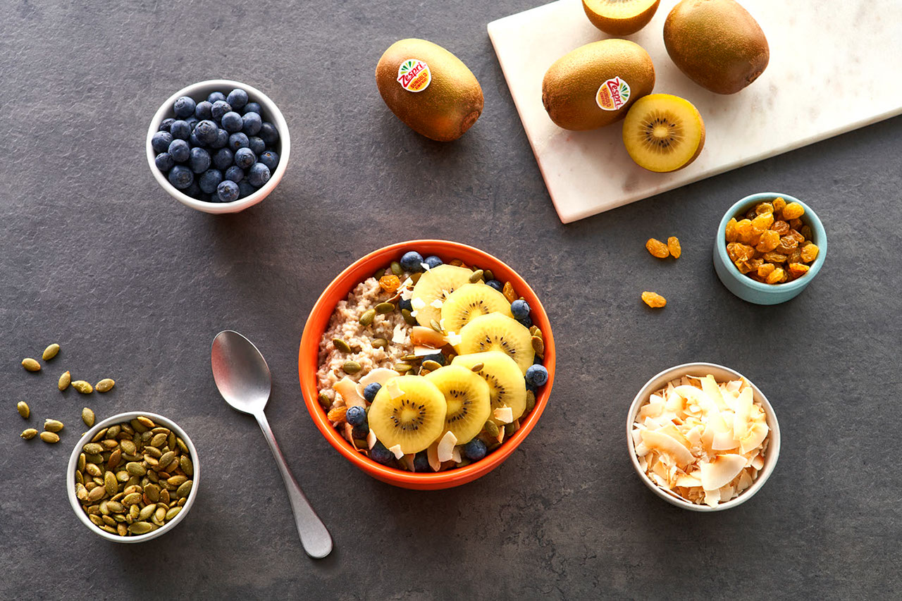 atmeal with Zespri SunGold kiwi and blueberries in orange bowl and spoon on the side