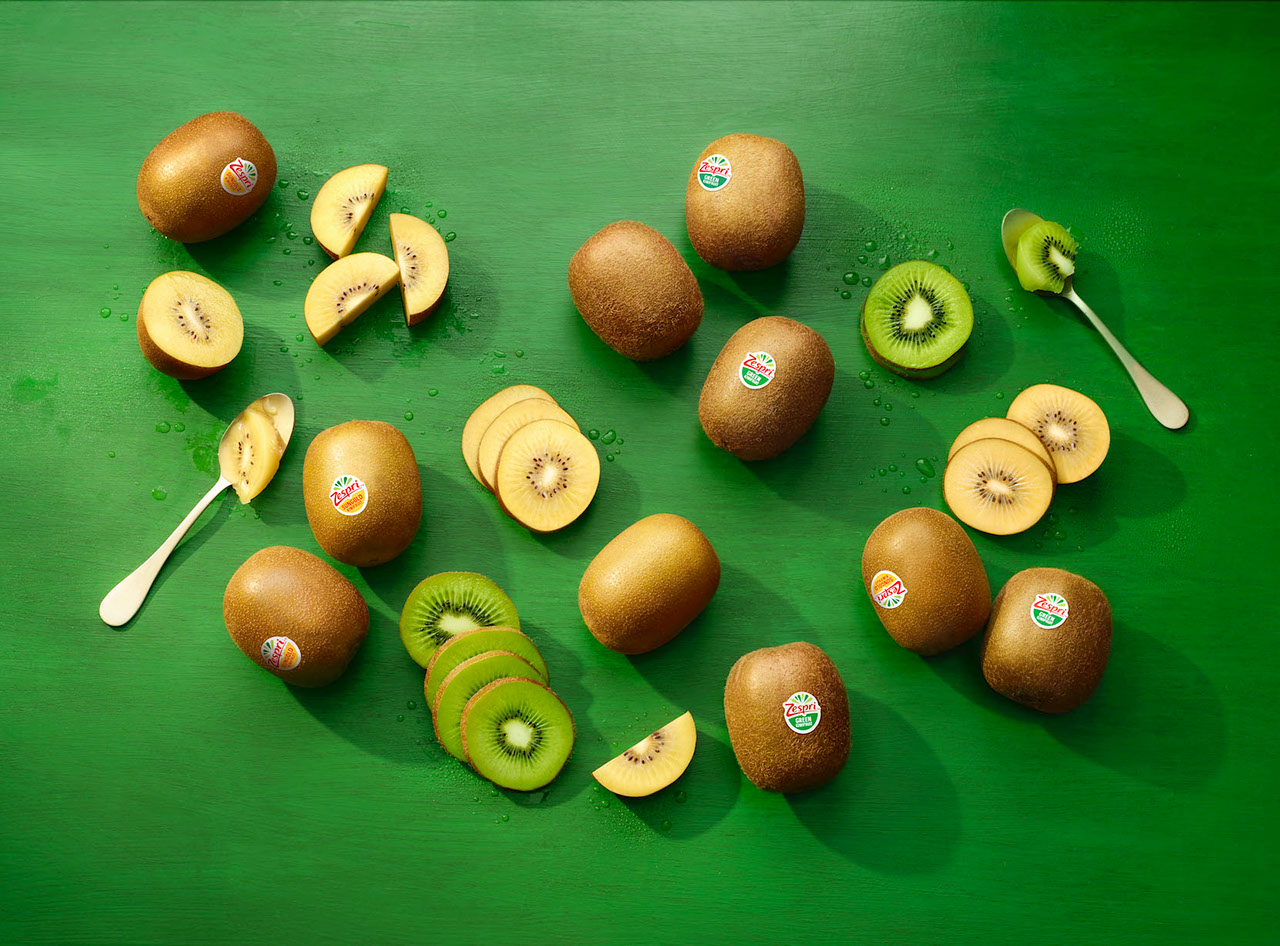Sliced and whole green kiwifruit and golden kiwi with spoons